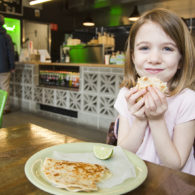 Little girls hold up quesadilla, smiling