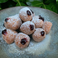 Plate of mini sufganiyot — powdered sugar–coated Hanukkah jelly doughnuts inspired by Sadie Davis-Suskind’s family recipe.