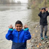 Hikes: two boys in raincoats holding their hands up next to the Snoqualmie river