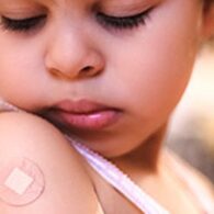 Child looks at bandaid on arm where RSV vaccine was administered at a Seattle pediatric clinic, part of efforts to protect babies and reduce winter hospitalizations.