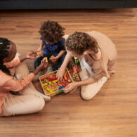 Diverse family with little son sitting on the floor at home and playing with wooden toys