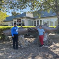 Two children stand in front of tall salmon statues at the Issaquah Salmon Hatchery.