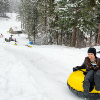 Woman in a tub at the top of the tubing hill smiles as she's about to go down