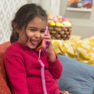 Child using a screen-free phone for kids in a playroom while learning phone etiquette at home